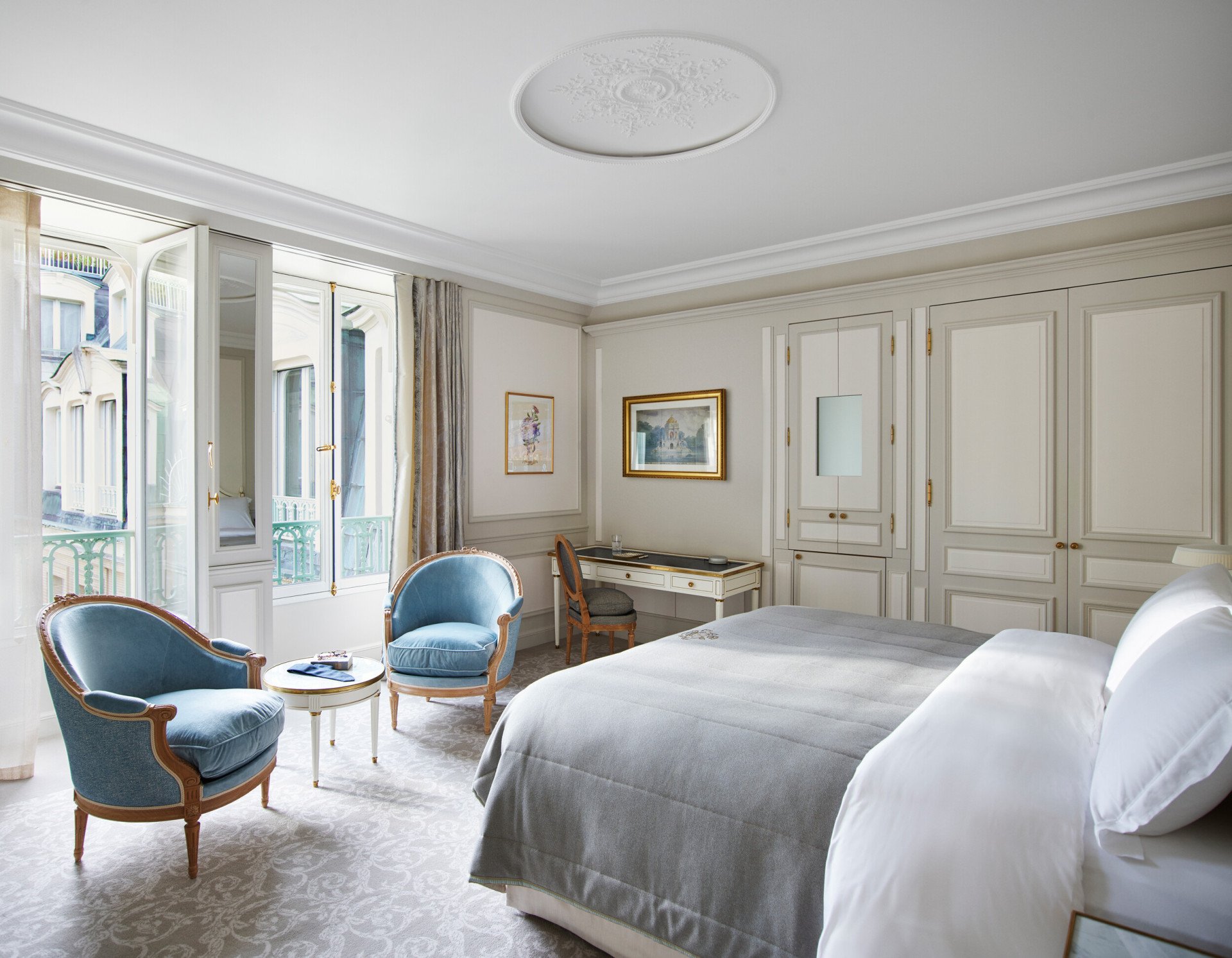 Bedroom of a deluxe suite with blue chairs at Le Meurice, Paris.