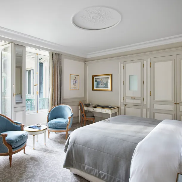 Bedroom of a deluxe suite with blue chairs at Le Meurice, Paris.