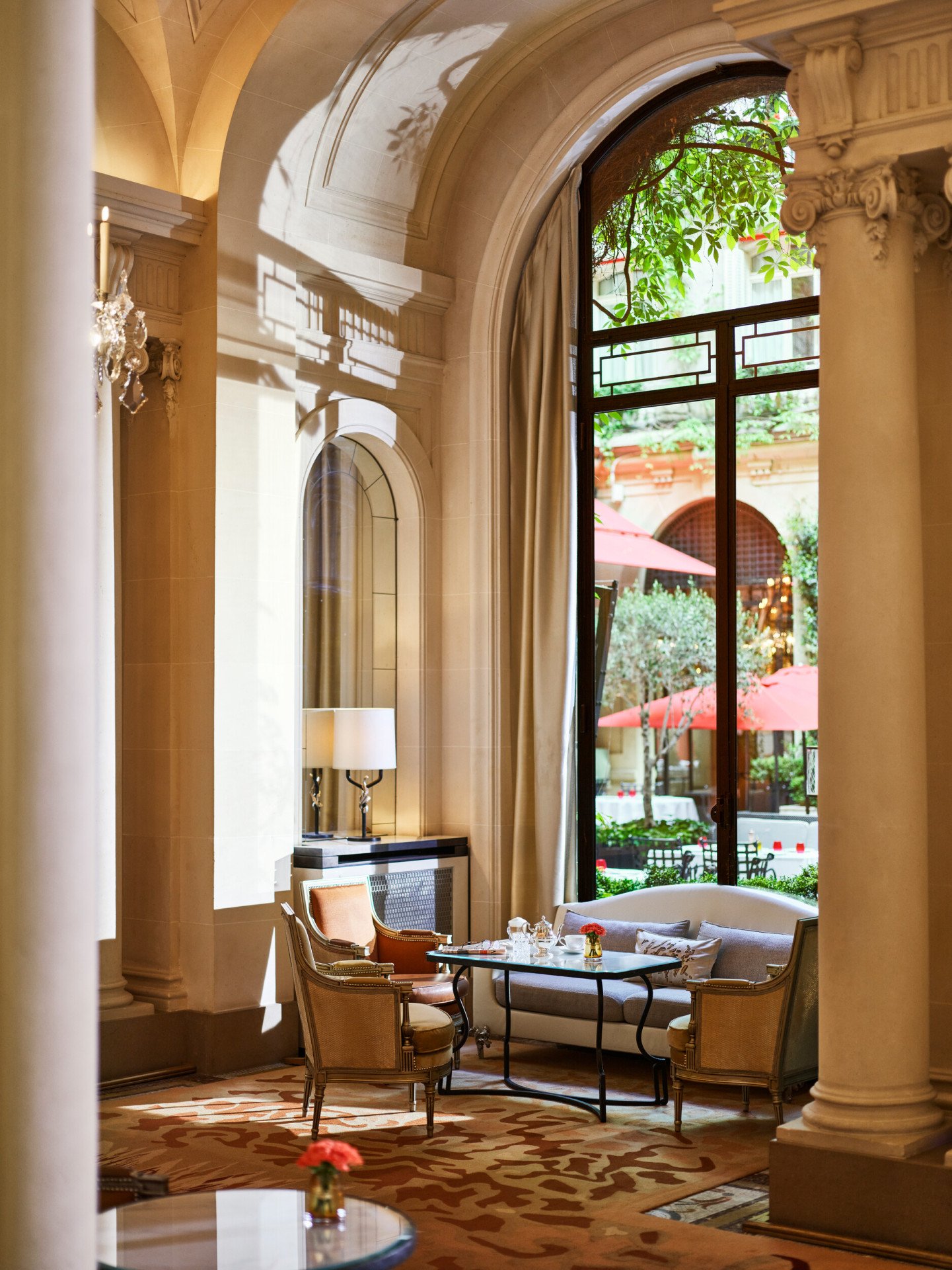 Dining table at la galerie, table with cups of tea, two armchairs and a sofa next to a sunny window giving on the Cour Jardin Courtyard, at Hotel Plaza Athénée, Paris