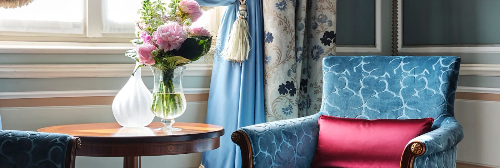 Detail shot of a Mosaic room including an armchair and flowers by the window