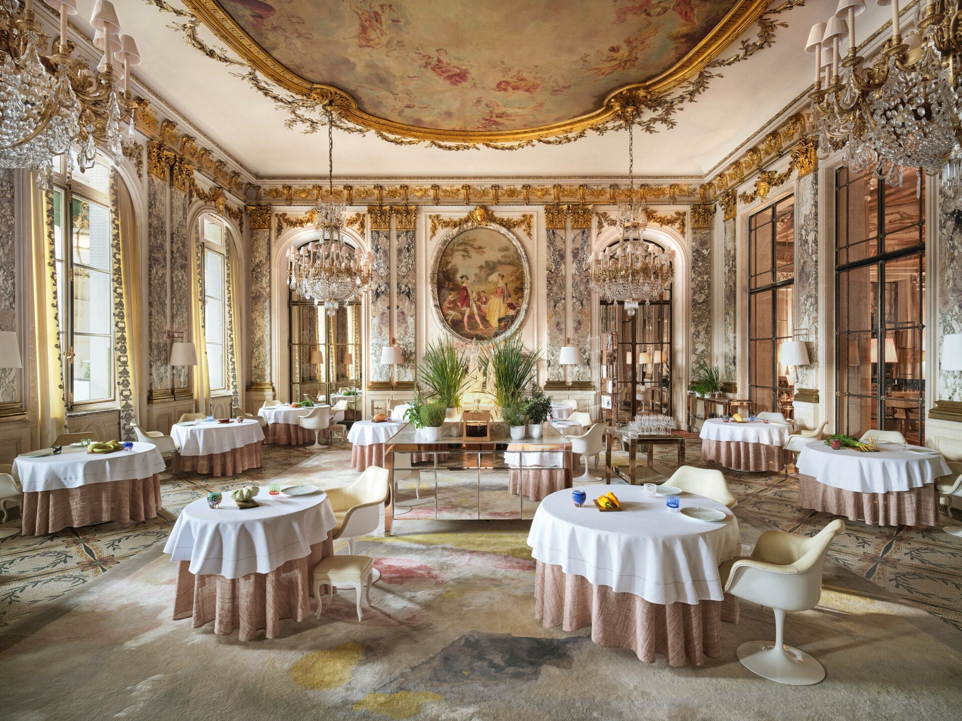 Large view of Le Restaurant le Meurice Alain Ducasse with the furnitures, the chandeliers, the plants and the food on the tables, at Le Meurice, Paris