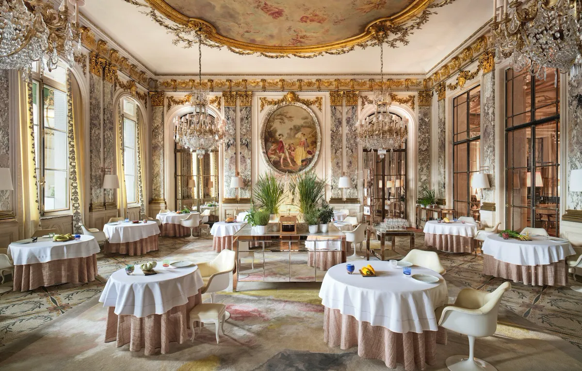 Large view of Le Restaurant le Meurice Alain Ducasse with the furnitures, the chandeliers, the plants and the food on the tables, at Le Meurice, Paris
