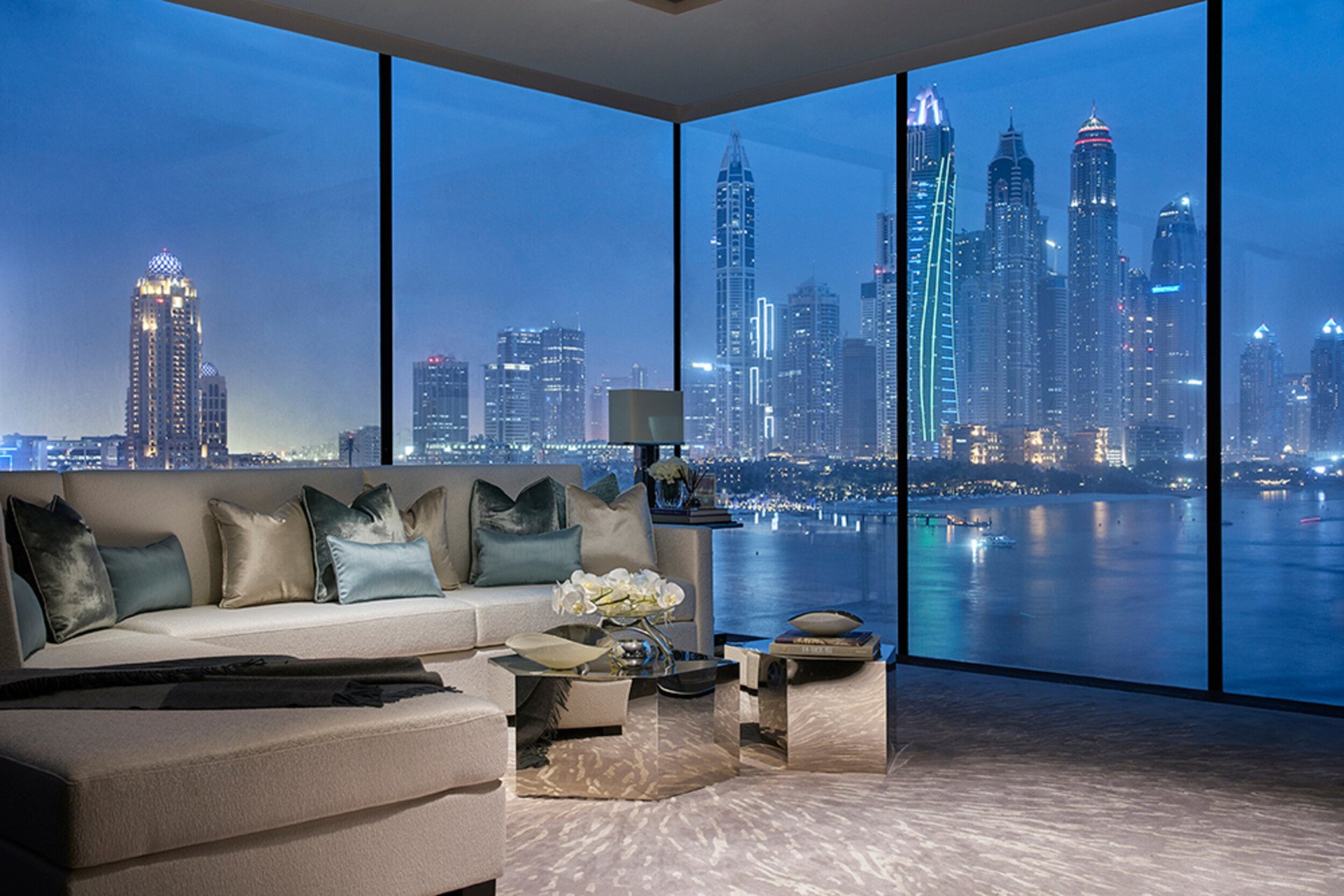 Living area with full height windows showing night time view of Dubai from One at Palm Jumeirah Residences