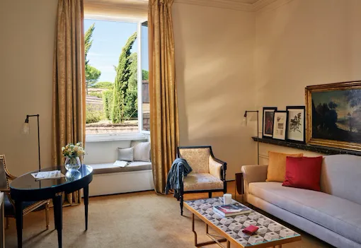 Living Room of Classic suite with open window, couch, armchair and desk at Hotel Eden, Rome