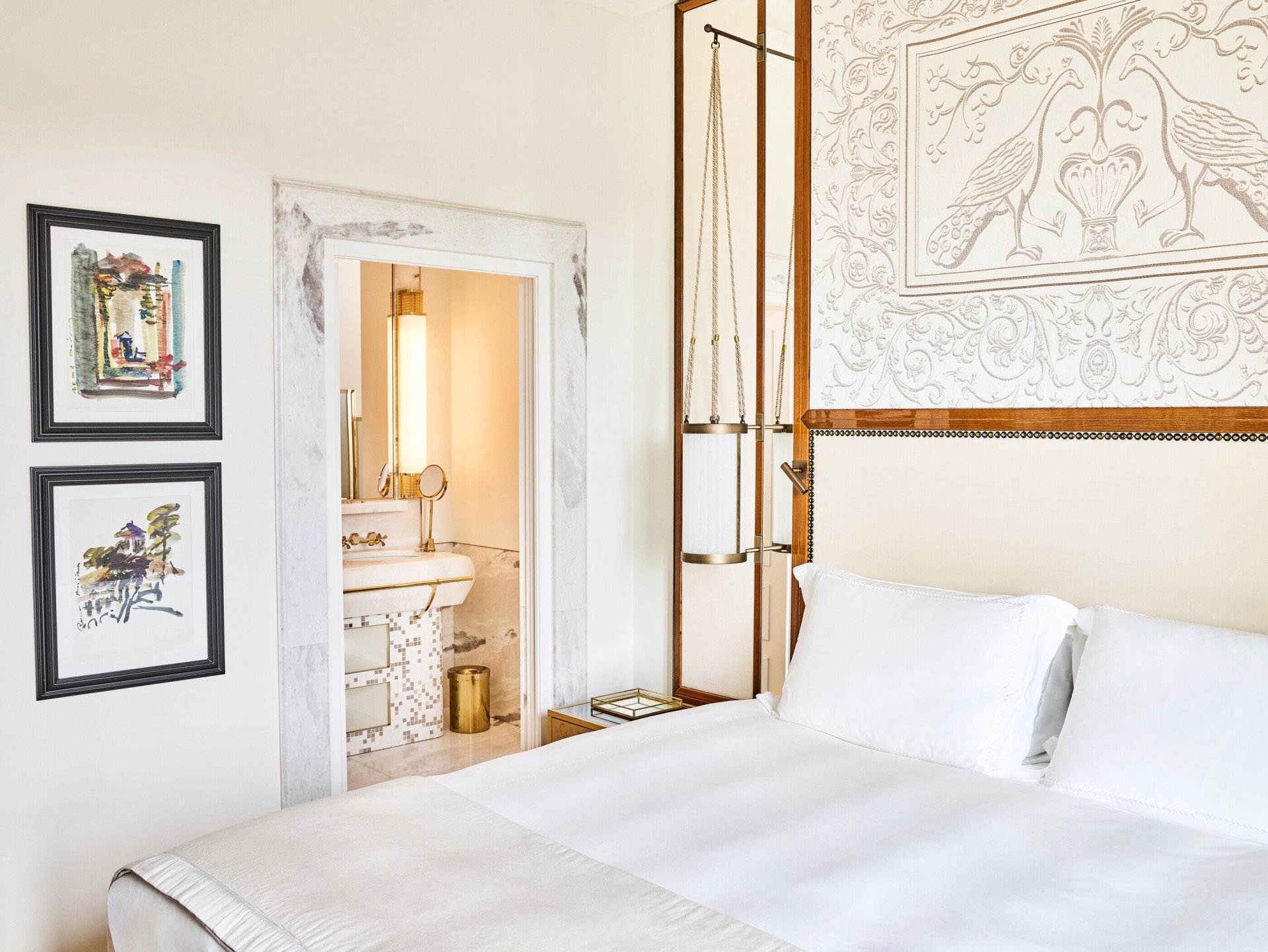 Bedroom of Classic suite with view with paintings on the wall and bathroom in the background at Hotel Eden, Rome
