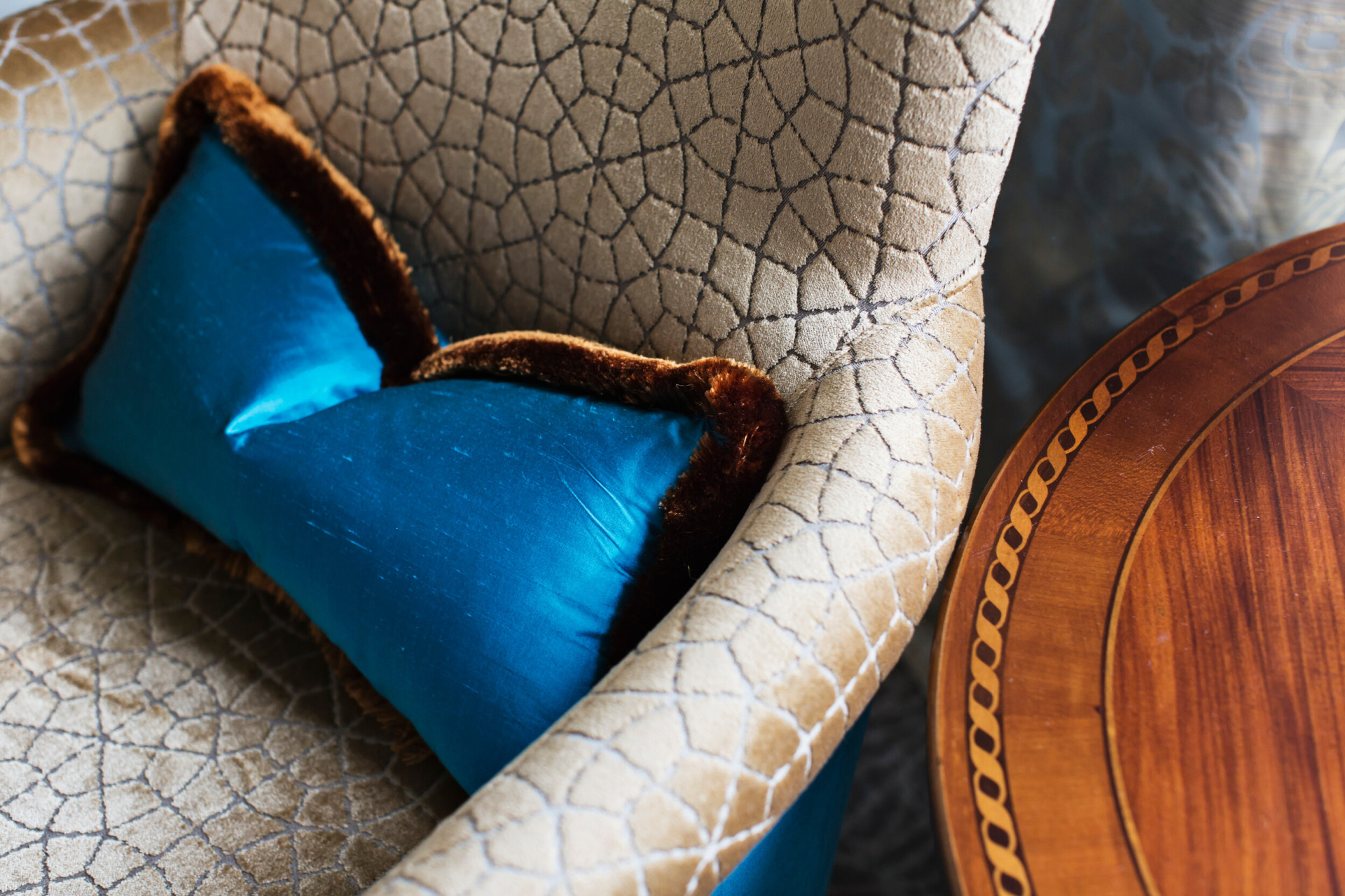 Detail of an armchair with blue pillow and wood coffee table