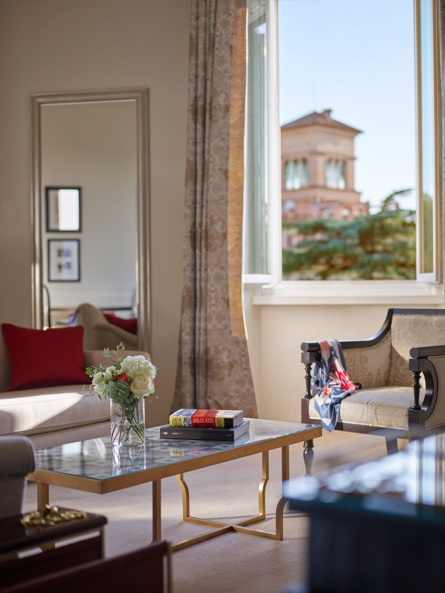 Living Room of Dolce Vita Suite with coffee table, couch, armchairs and windows open to view of Rome at Hotel Eden