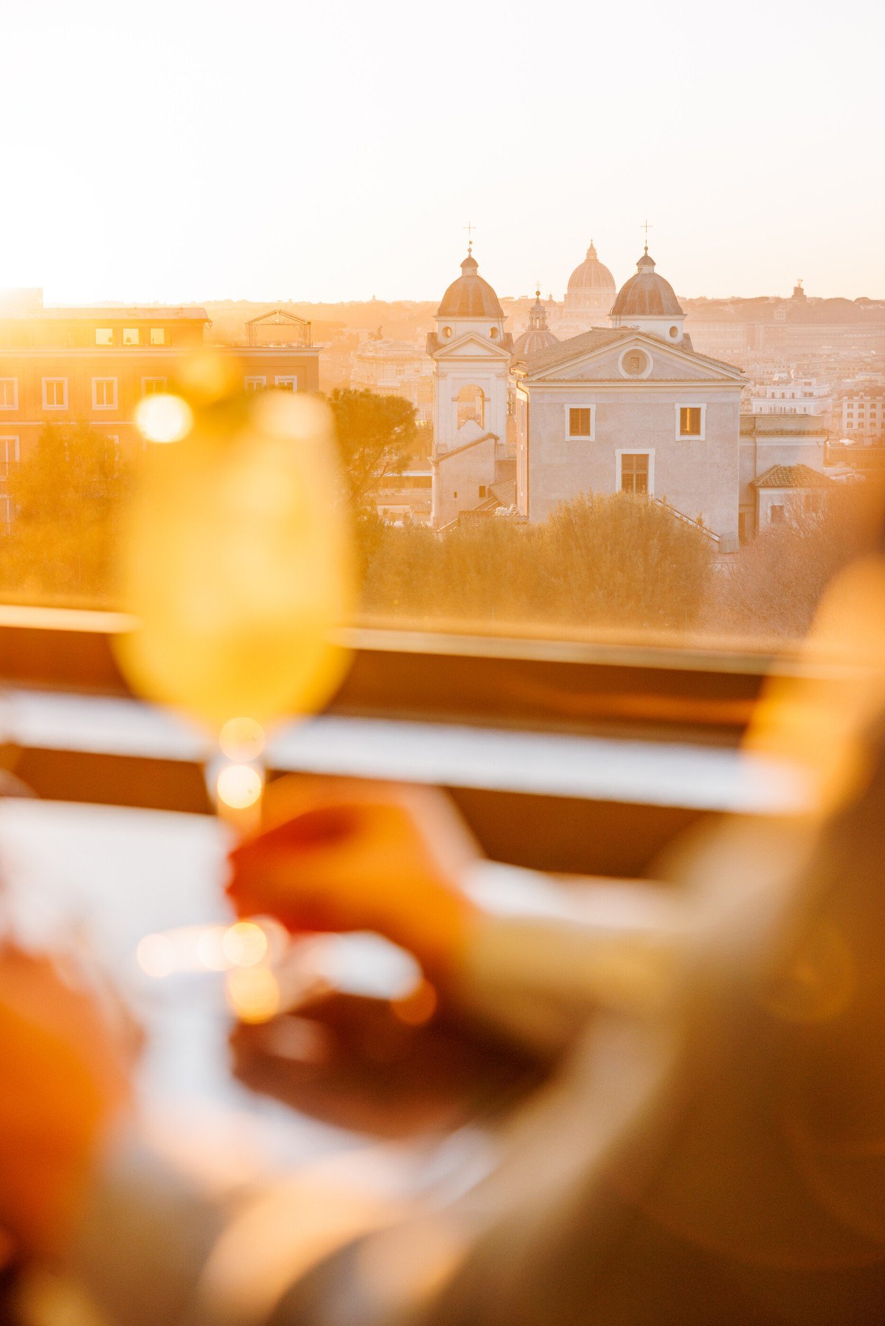 Hand grabbing a drink with Rome sunset view on background at Il Giardino Bar 