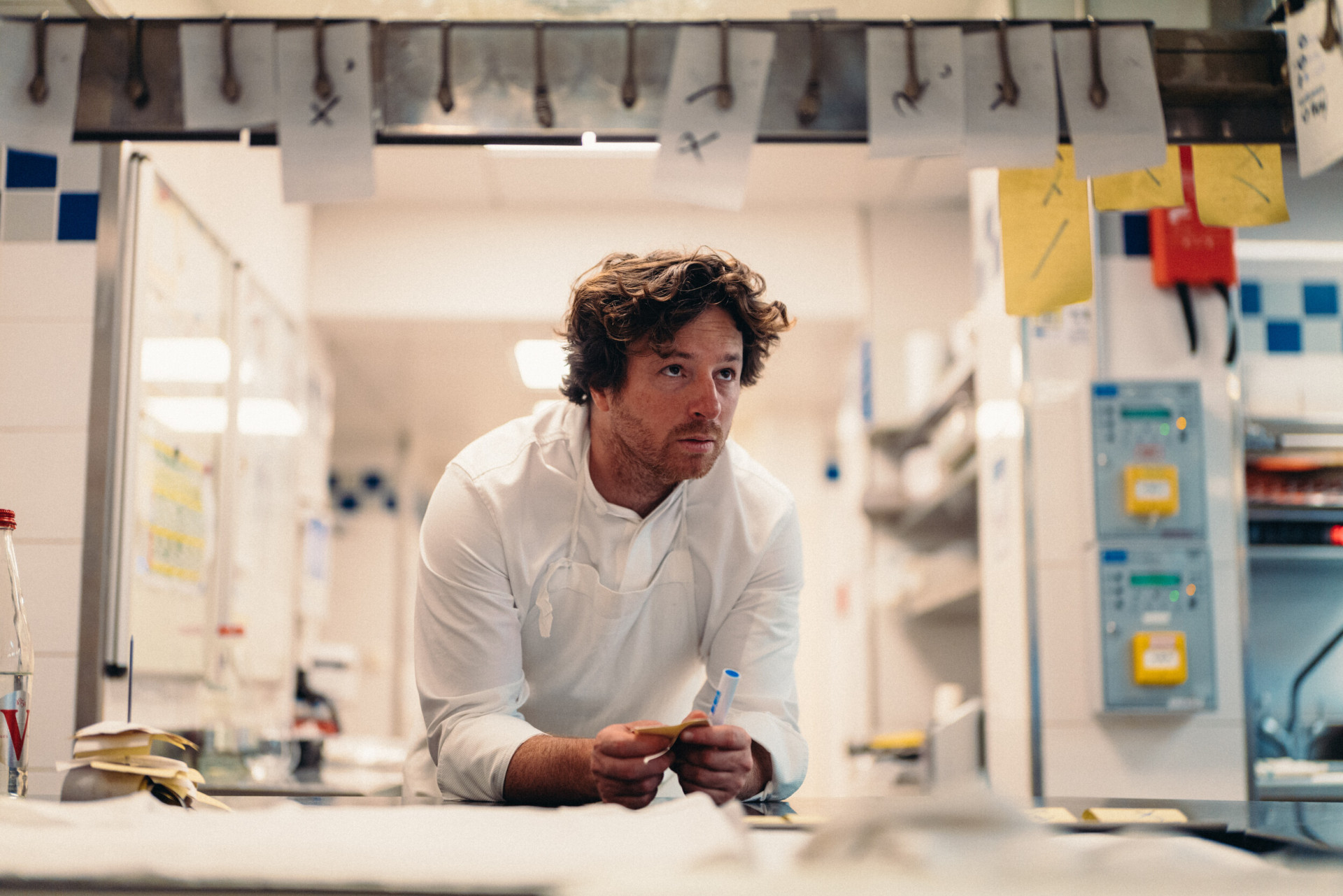 Backstage picture of Chef Jean Imbert leaning on the kitchen counter at Hotel Plaza Athénée, Paris