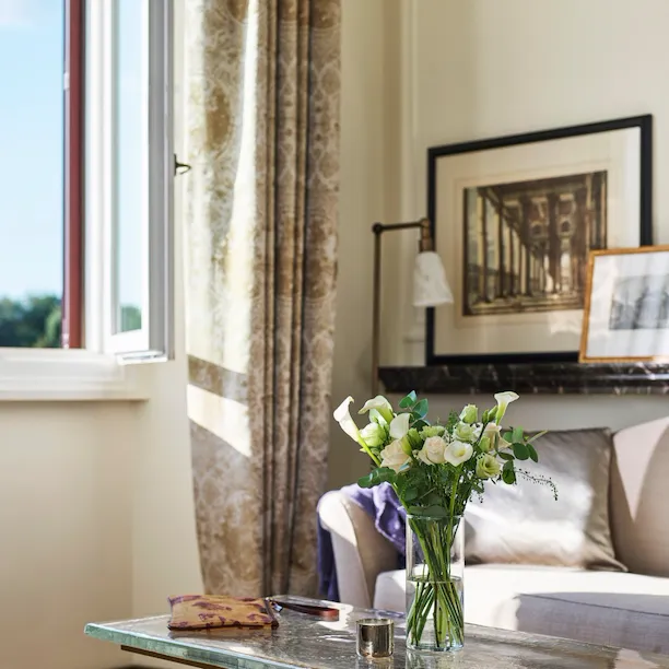 Detail of coffee table with bouquet of flowers and couch of Classic suite with view at Hotel Eden, Rome