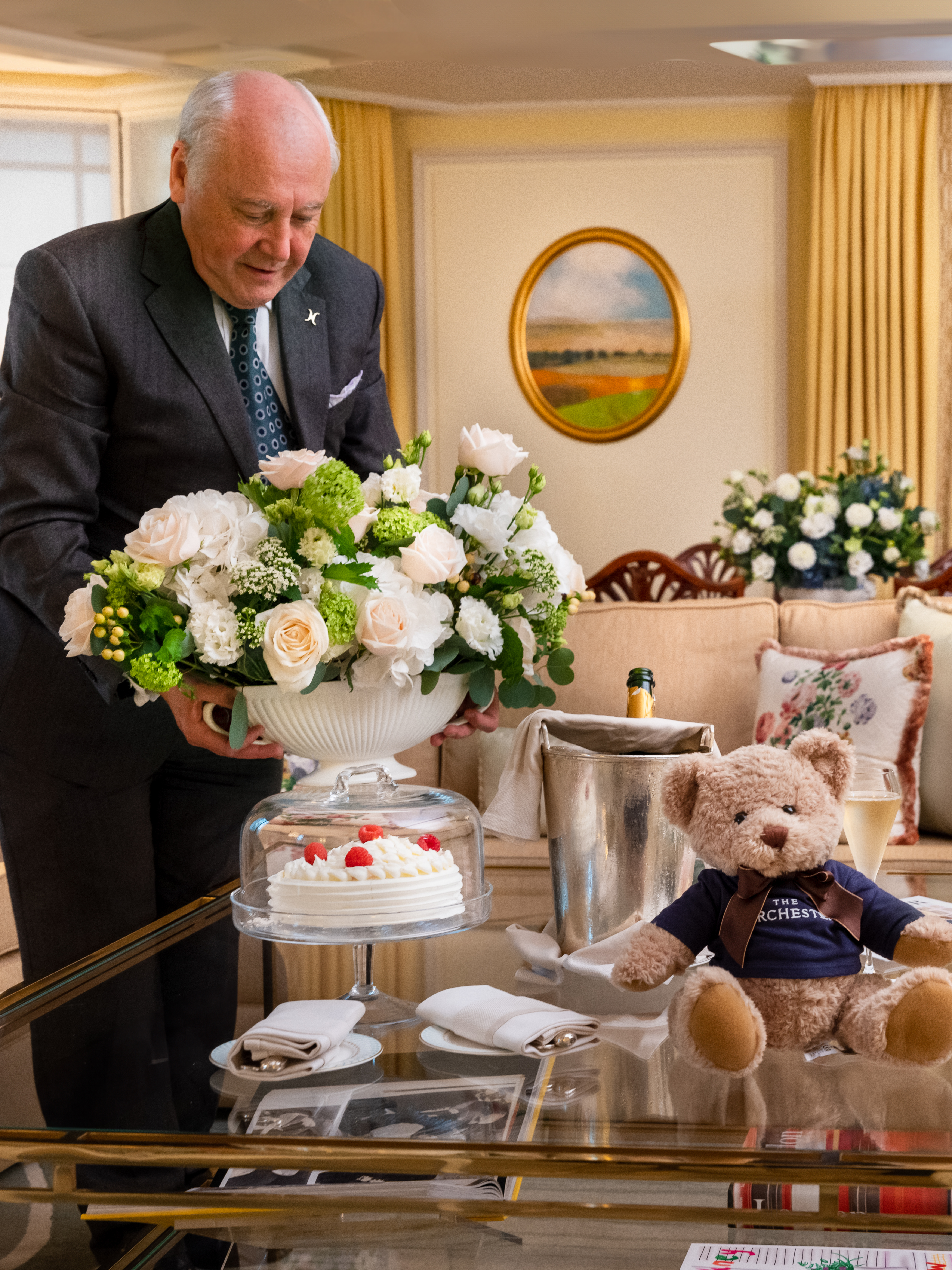 Butler in Dorchester suite with floral arrangement, champagne and Dorchester teddy bear