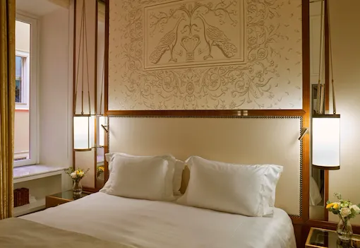 Bedroom of Classic suite and headboard with peacocks decoration at Hotel Eden, Rome