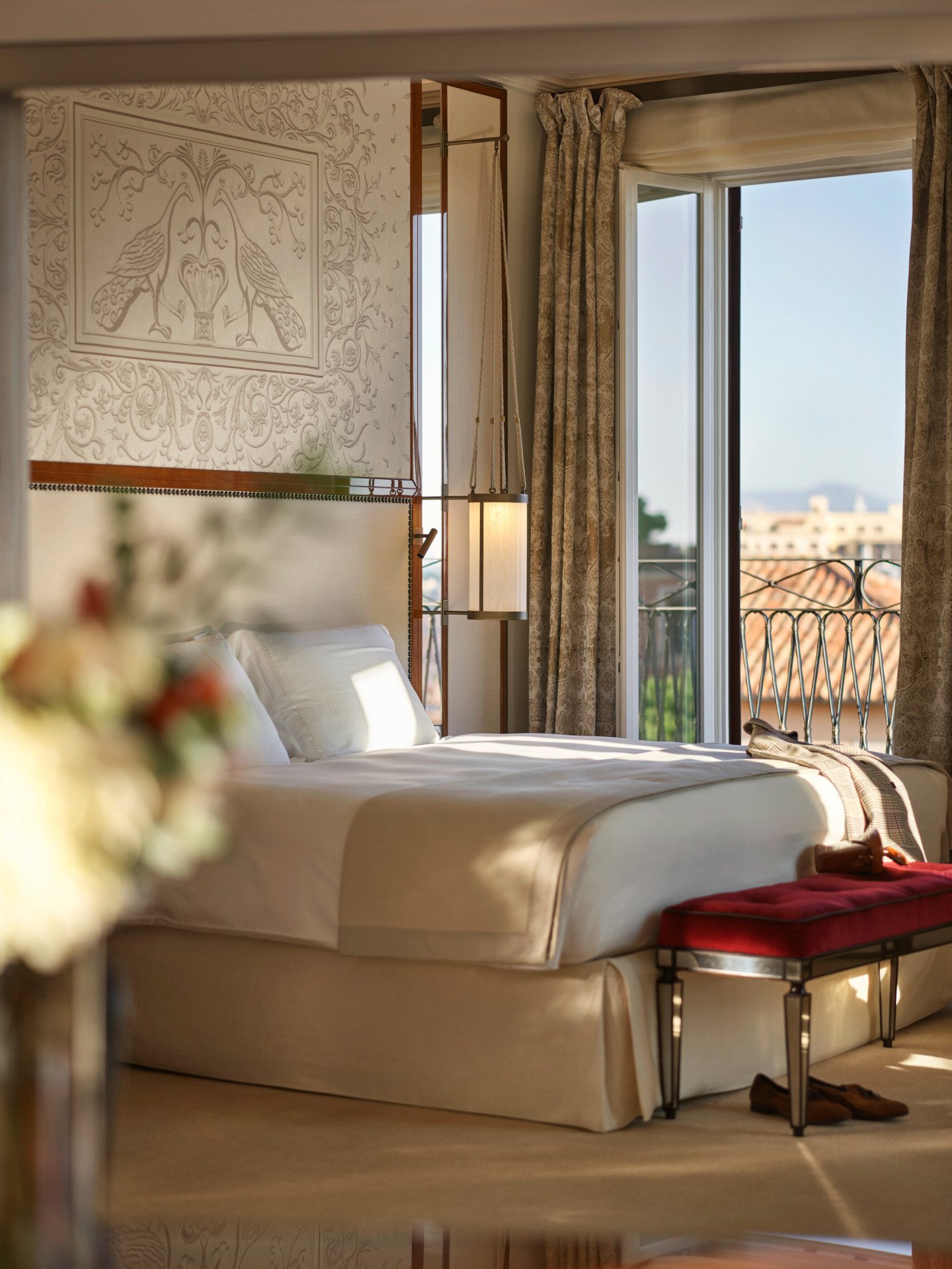 Elegant bedroom Presidential Suite, headboard with peacocks decoration and big window with view of Rome at Hotel Eden