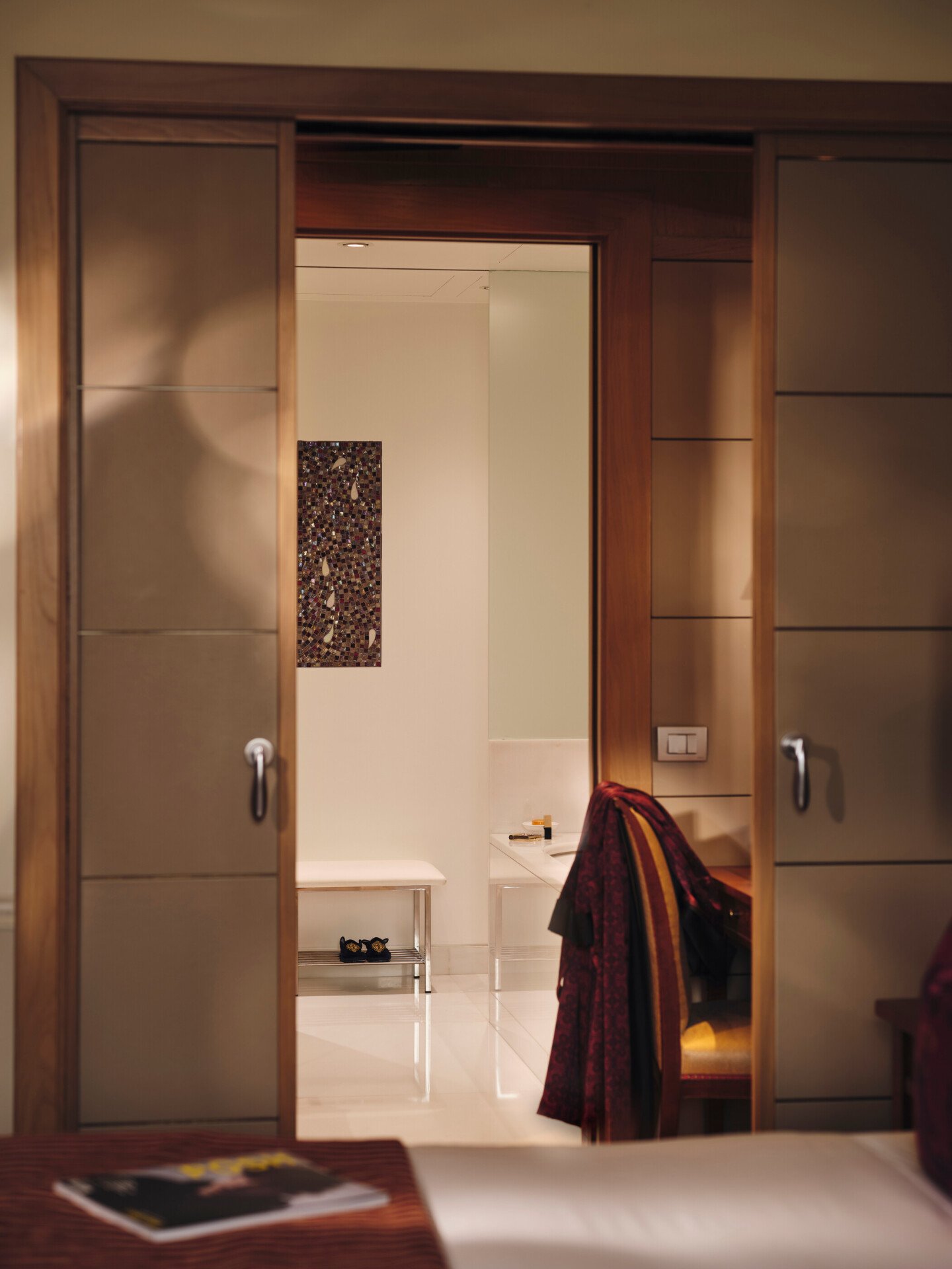View of the bathroom from the Mosaic Room with a magazine in the foreground and a red robe in the background