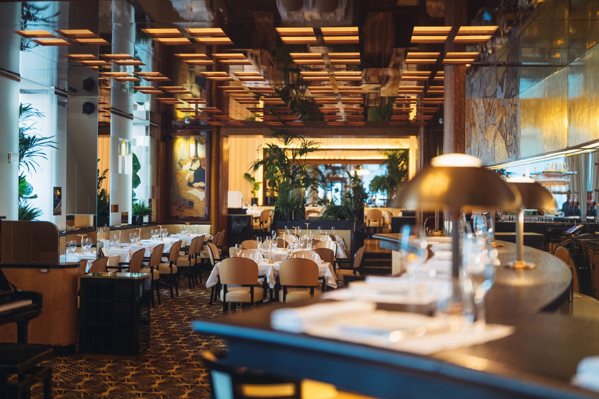 Overview of Le Relais Plaza's dining room lower deck, with the bar at the forefront,at Hotel Plaza Athénée, Paris