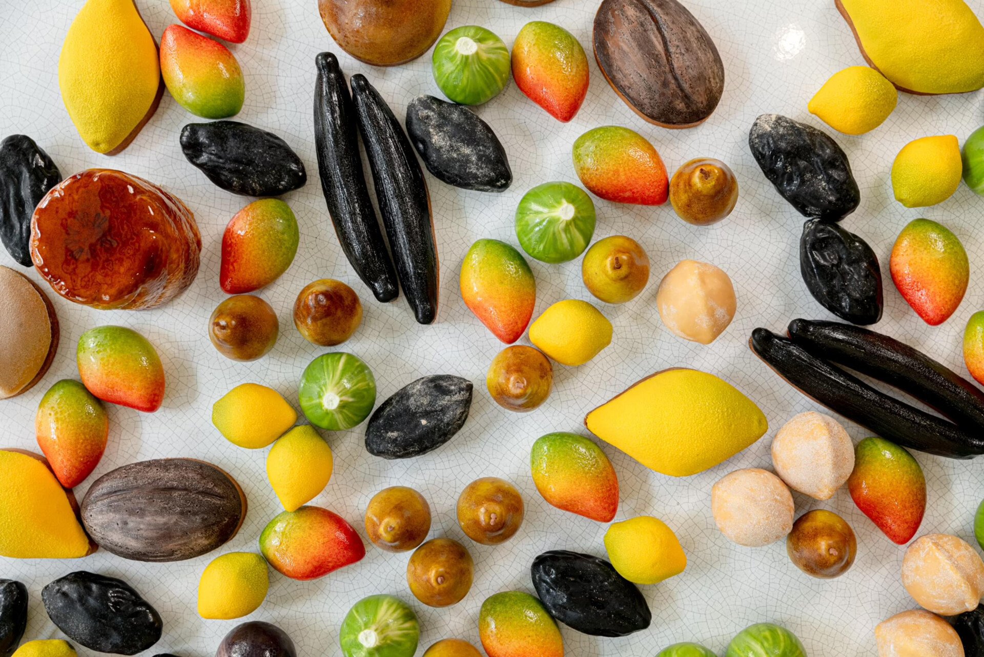 We can observe a large panel of fruit pastries, "trompe l'oeil" style, from a top view. Among them : lemons, vanilla beans, pears, mangoes and more, at Le Meurice, Paris. 