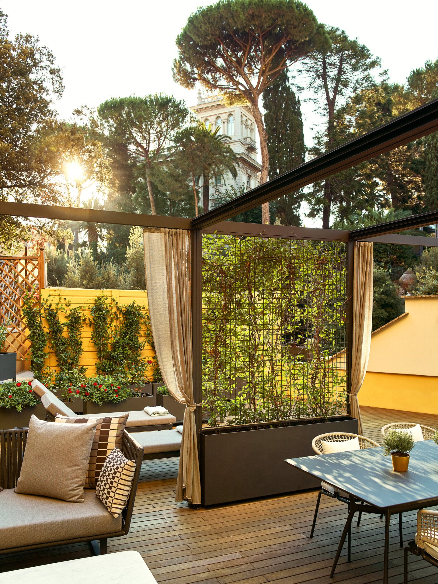 Sunny terrace with plants, couch, table for al fresco dining at Aurora Terrace Suite at Hotel Eden, Rome