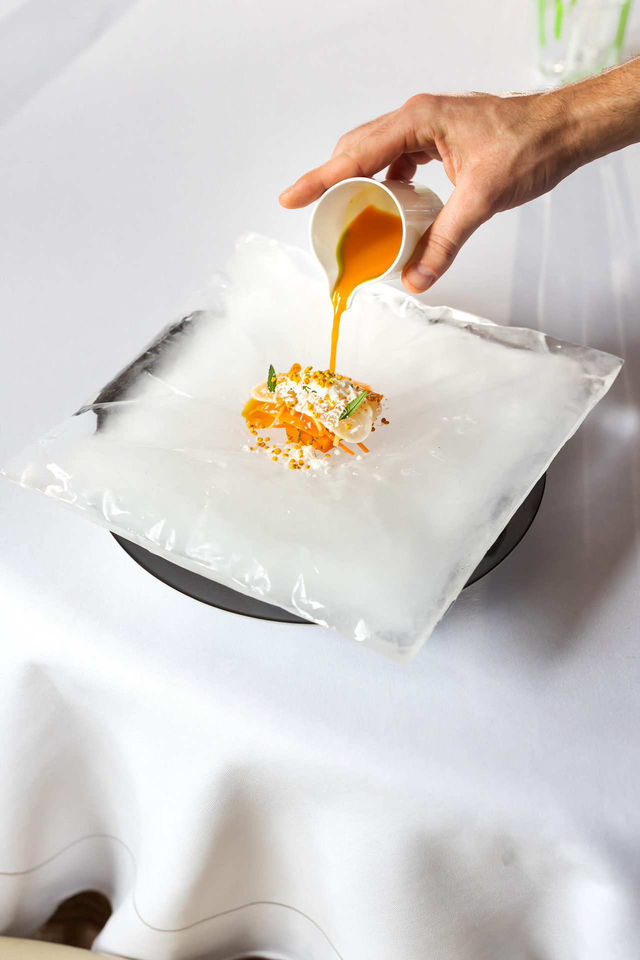 Hand serving sauce over sea bream with carrots at Restaurant Le Meurice Alain Ducasse, at Le Meurice, Paris.