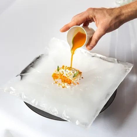 Hand serving sauce over sea bream with carrots at Restaurant Le Meurice Alain Ducasse, at Le Meurice, Paris.