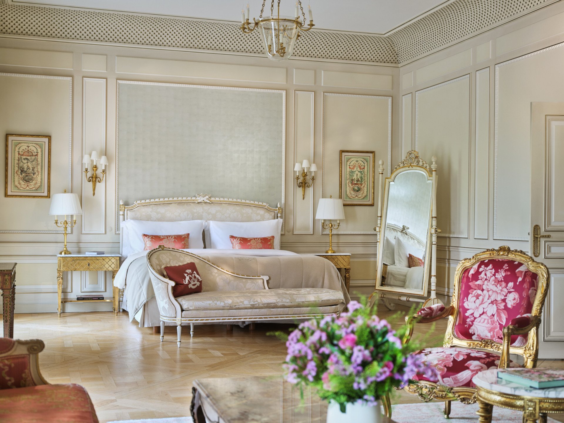 Large view of a Versailles suite with on the foreground a bouquet of flowers and chairs, and behind a couch close to the bed, at Le Meurice, Paris