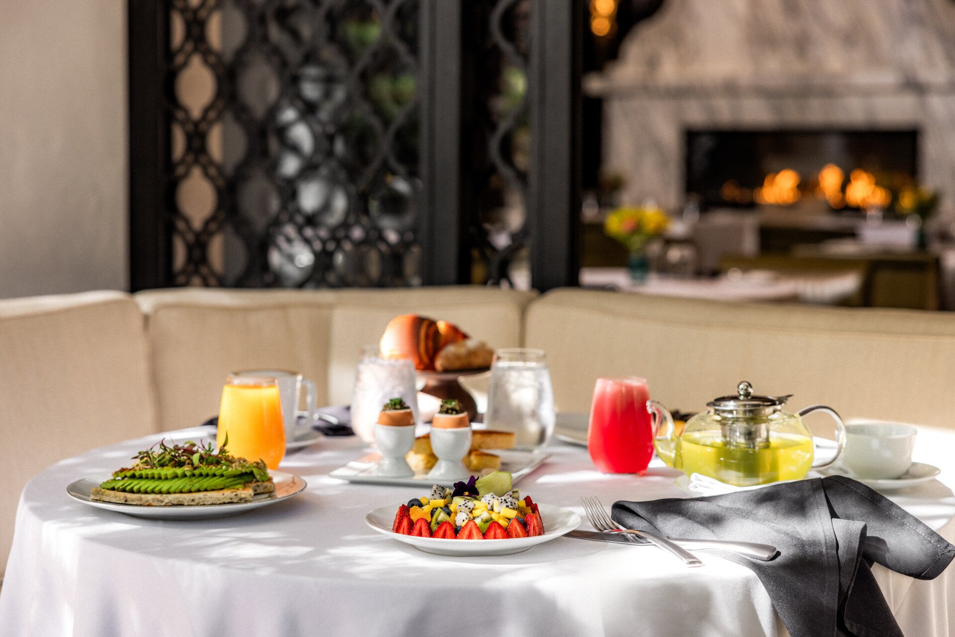 Breakfast at The Restaurant table spread featuring fruit platter, avocado toast, and juices