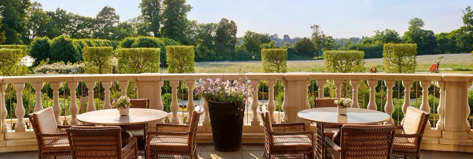 Coworth Park Drawing Room Terrace tables in afternoon sunshine overlooking grass fields