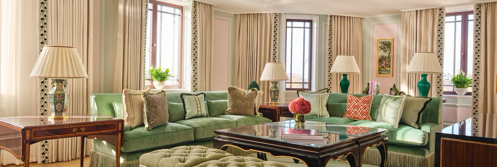 Elegant living room with green sofas, lamps, windows, and decorative rugs creating a cozy atmosphere