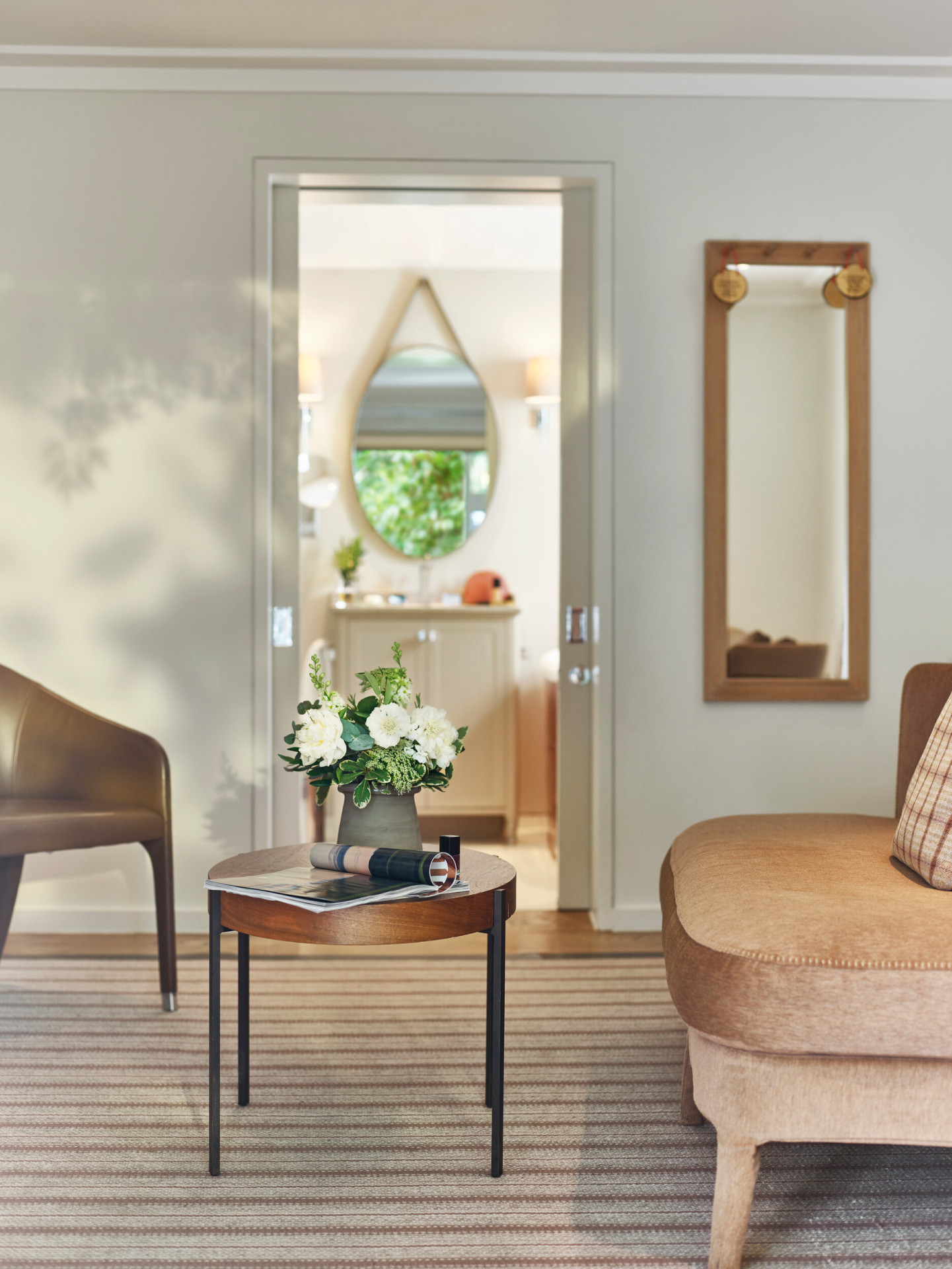 Coworth Park-Stable Junior suite-Loft Cottage-living room with floral bouquet on the table and view through to the bathroom 