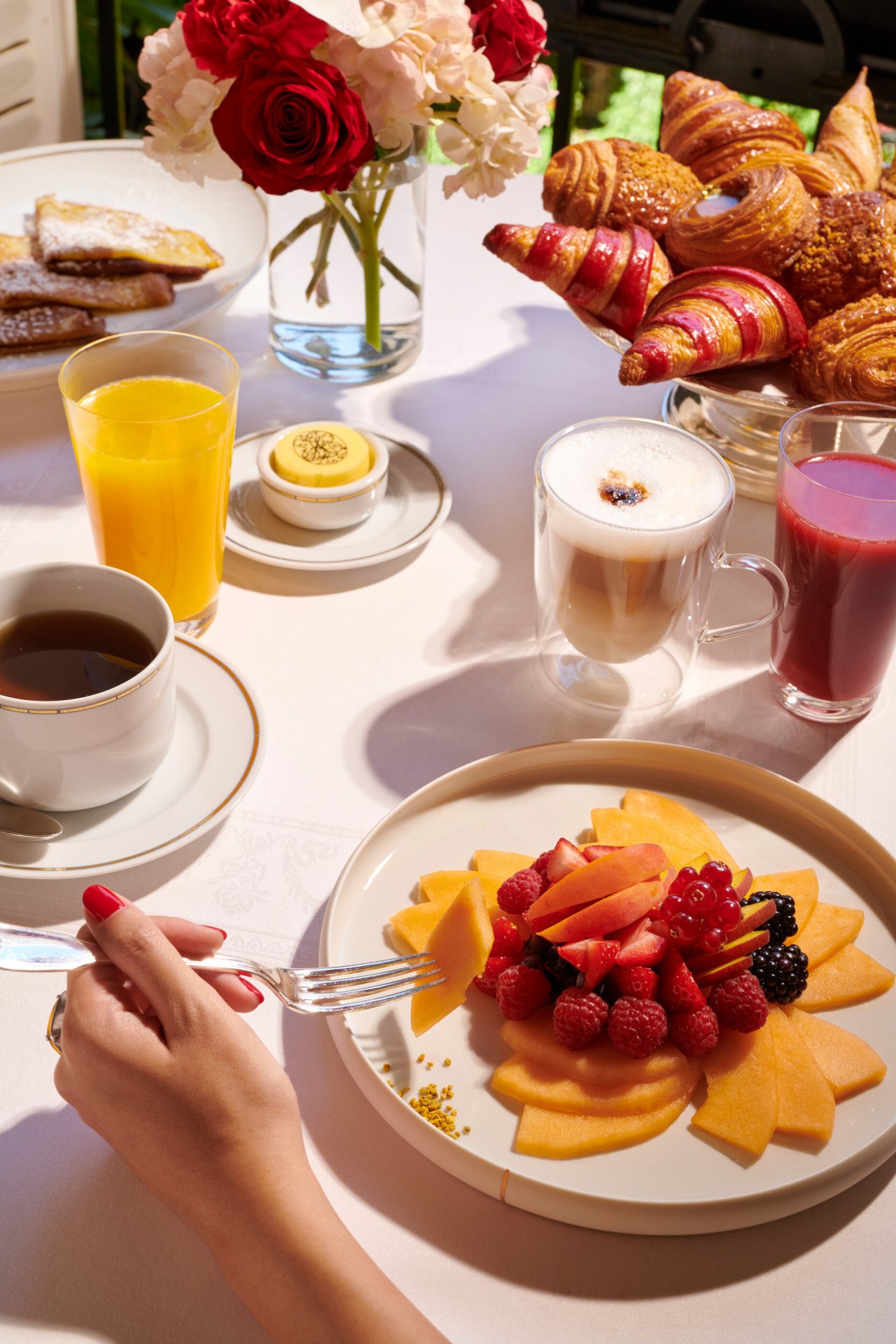 Images of the brunch at the Jean Imbert au Plaza Athénée. We can see a hand picking fruits from a fruit salade plate