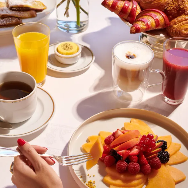 Images of the brunch at the Jean Imbert au Plaza Athénée. We can see a hand picking fruits from a fruit salade plate