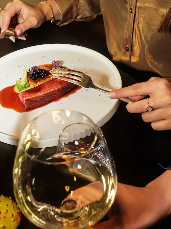 Woven by Adam Smith guests dinging waiting a Duck breast. The guest is wearing a gold shirt.