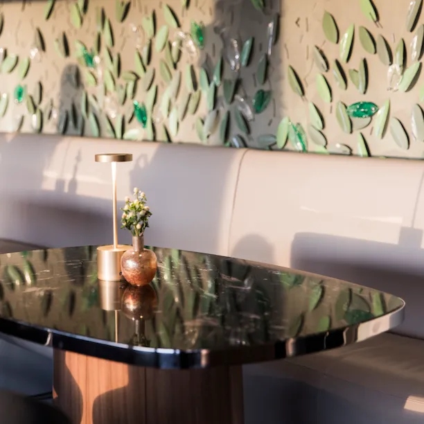 Interior of Il Giardino Bar with table and vertical garden wall with metal leaves at Hotel Eden, Rome