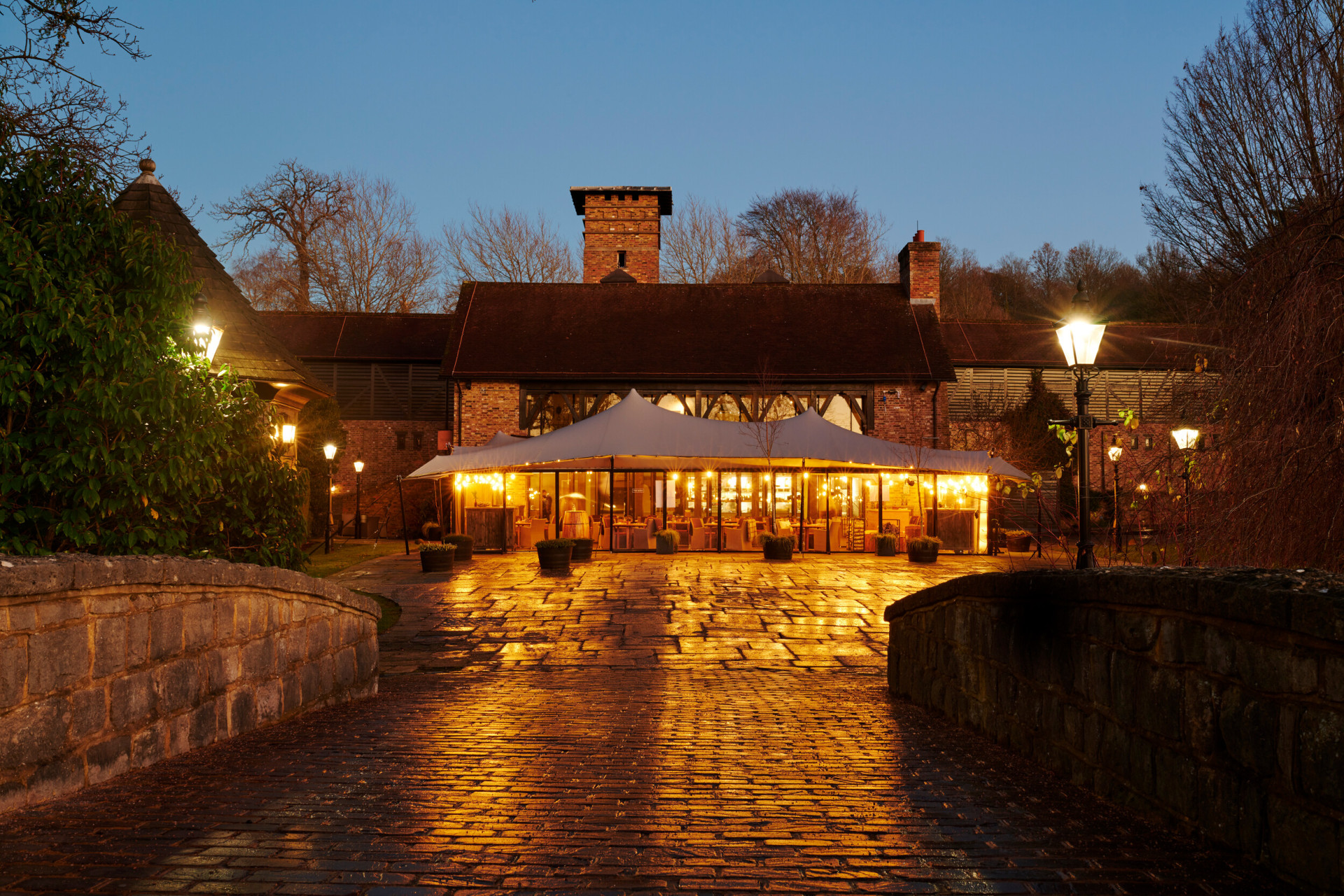 Coworth Park, The Barn, exterior at night with golden light 