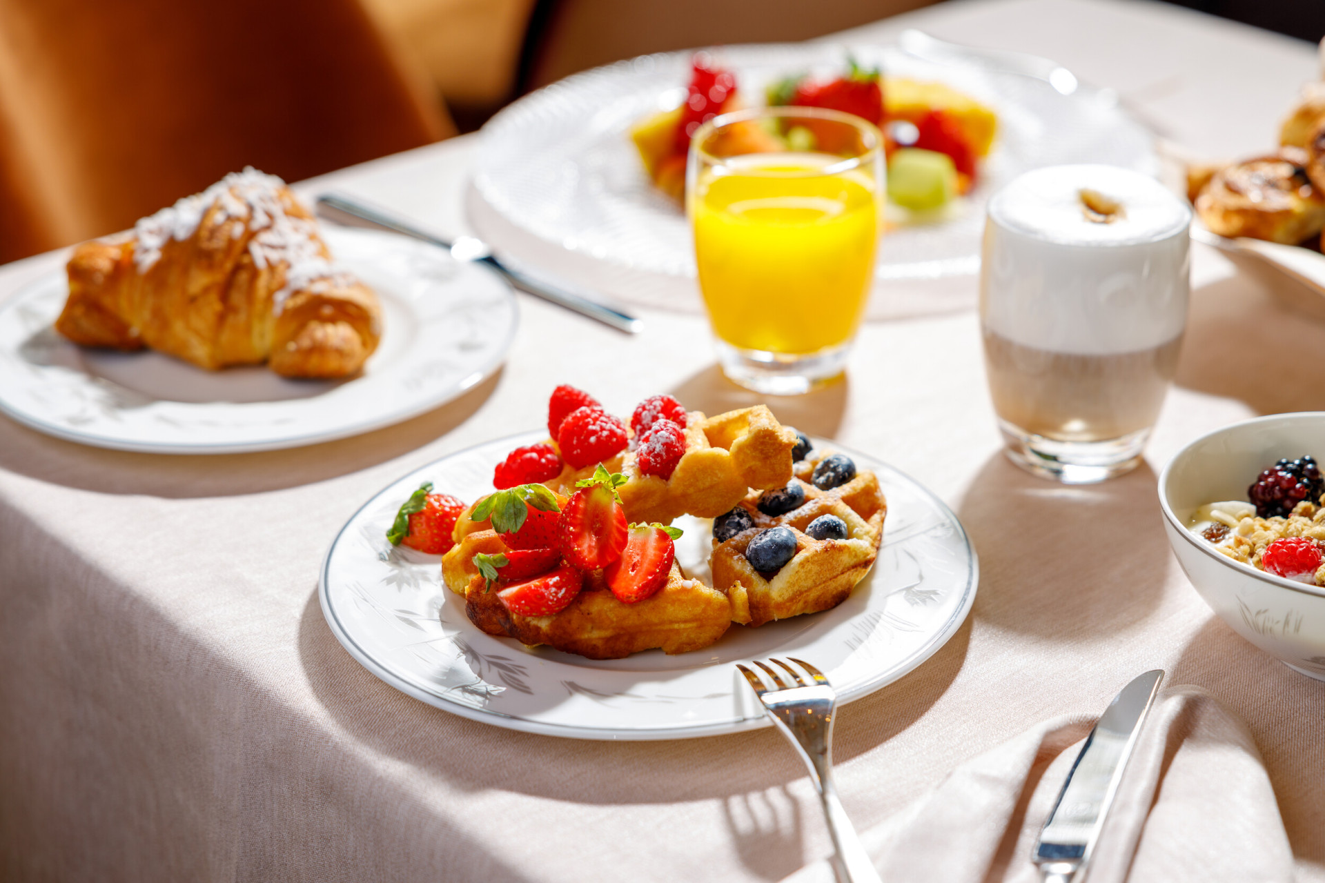 Acanto breakfast with waffles, croissants, a cappuccino and a yellow smoothie 