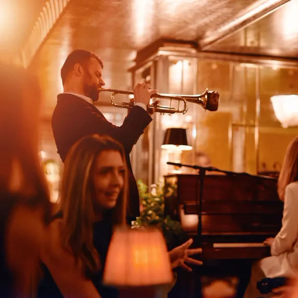 Two people playing trumpet and piano in the Vesper Bar in warm, evening light