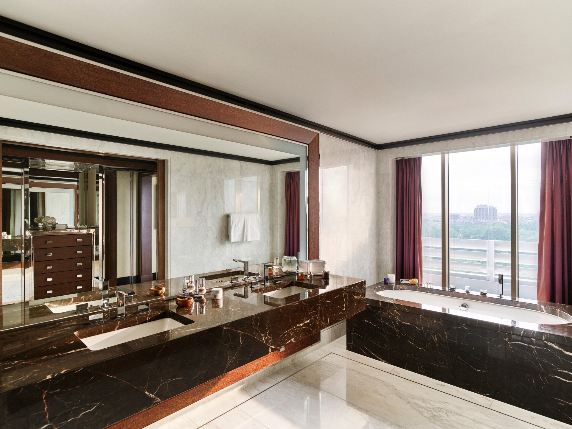 Bright hotel room with a marble vanity, large window, and mirror reflecting the space.