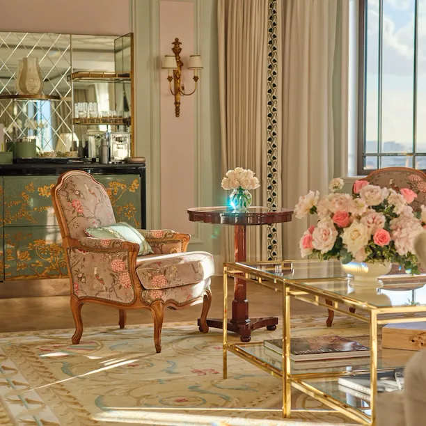 Elegant living room with a floral arrangement, sunlight, vintage furniture, and classic decor.