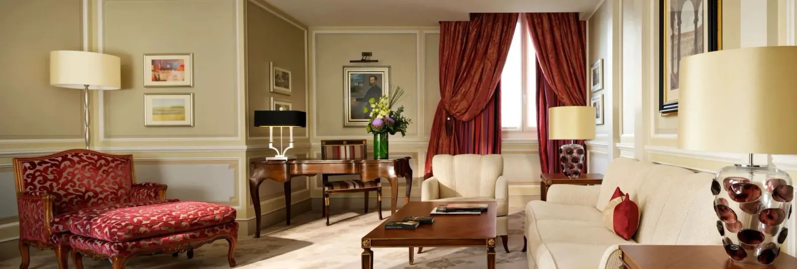 Principe Suite living room with red elements and a bouquet of flowers on the desk in the background