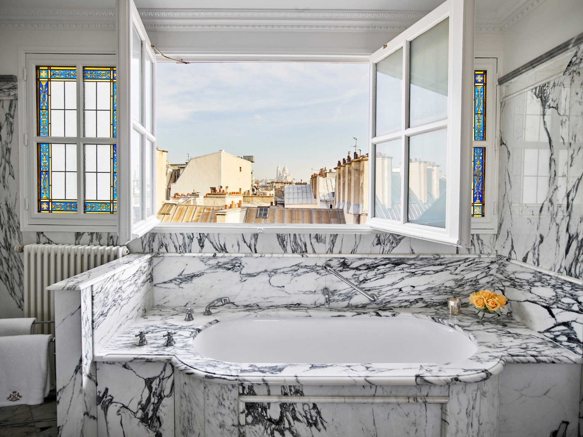 Marble bathroom with open windows overlooking roofs of Paris in an executive junior suite at Le Meurice, Paris.
