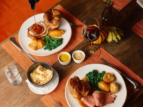 Sunday roast in The Barn at Coworth Park with seasonal vegeatbles, roast potatoes, yorkshire puddings and gravy. Accompanied by red wine.