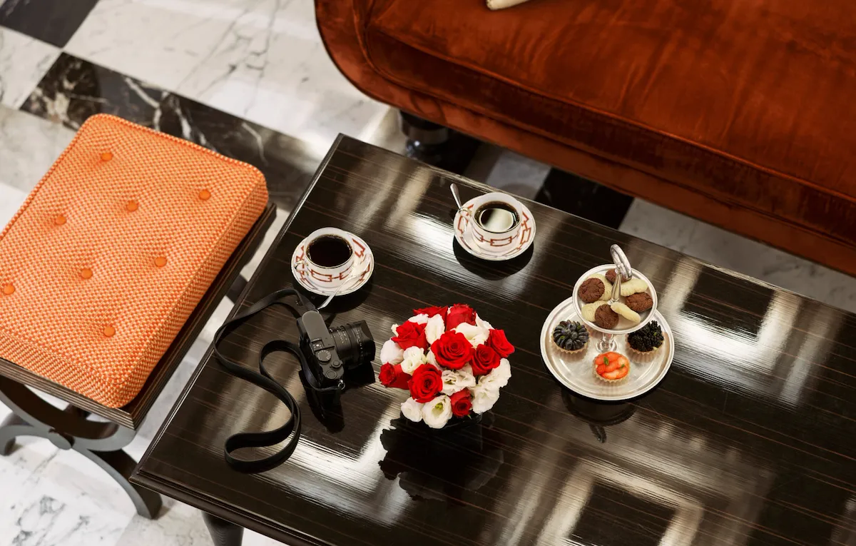 Coffee table with flowers, pastries, two coffee cups and a camera at La Libreria at Hotel Eden, Rome