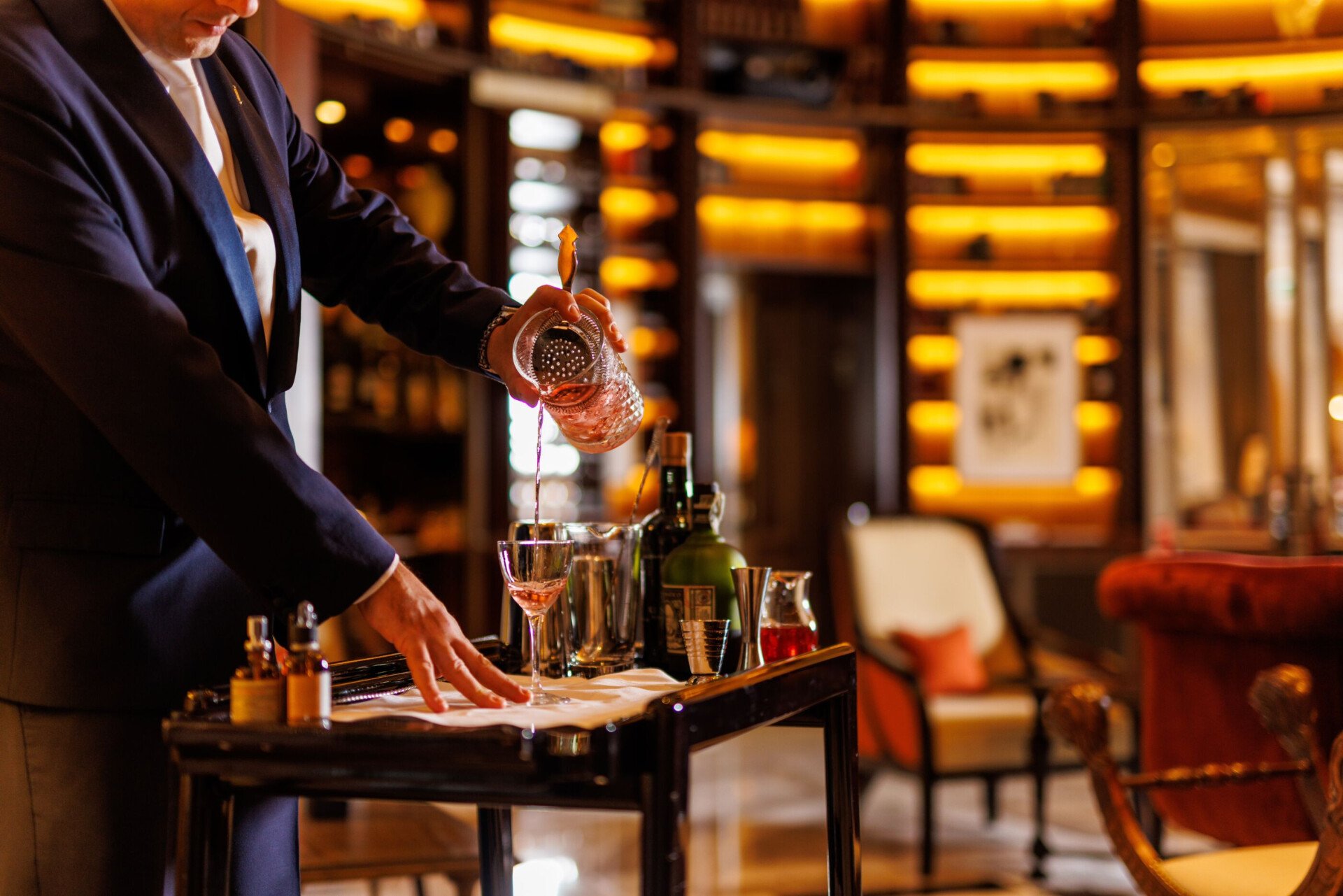 Barman pouring cocktail at the drinks trolley