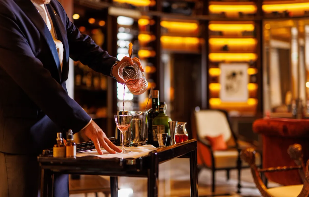 Barman pouring cocktail at the drinks trolley