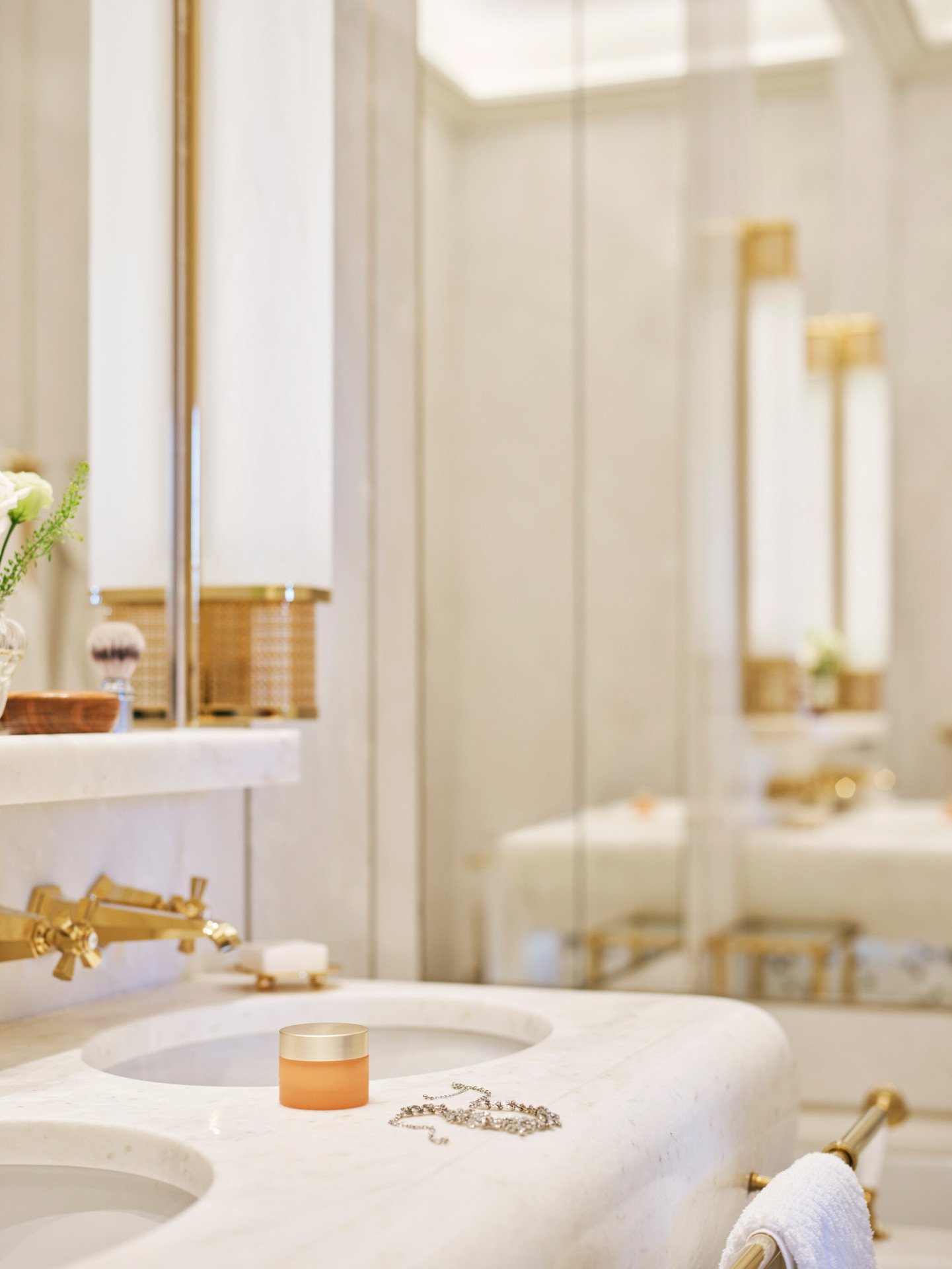Bathroom with face cream and necklace on white marble sink at Classic Suite with view at Hotel Eden, Rome