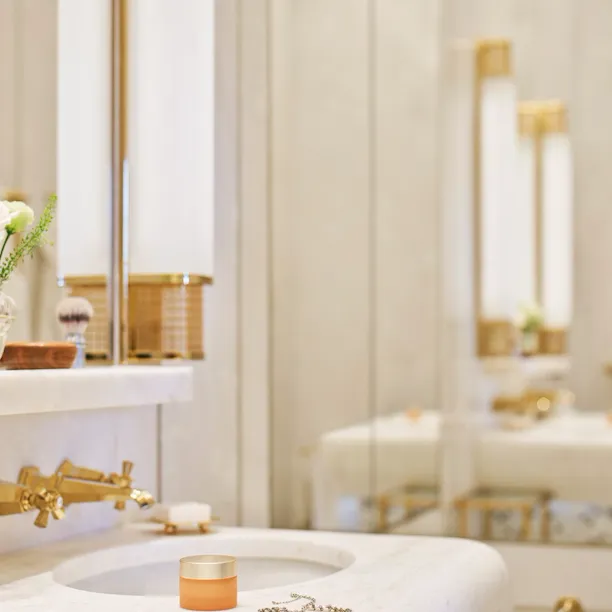 Bathroom with face cream and necklace on white marble sink at Classic Suite with view at Hotel Eden, Rome