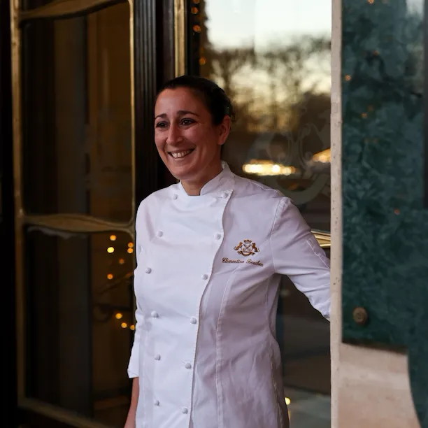 We can see our chef Clementine standing smiling in front of the doors at Le Meurice, Paris.