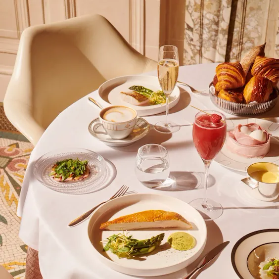 Top view of a brunch table with chicken breast with a glass of champagne, of cocktail and a cup of coffee at Le Meurice, Paris - Dorchester Collection