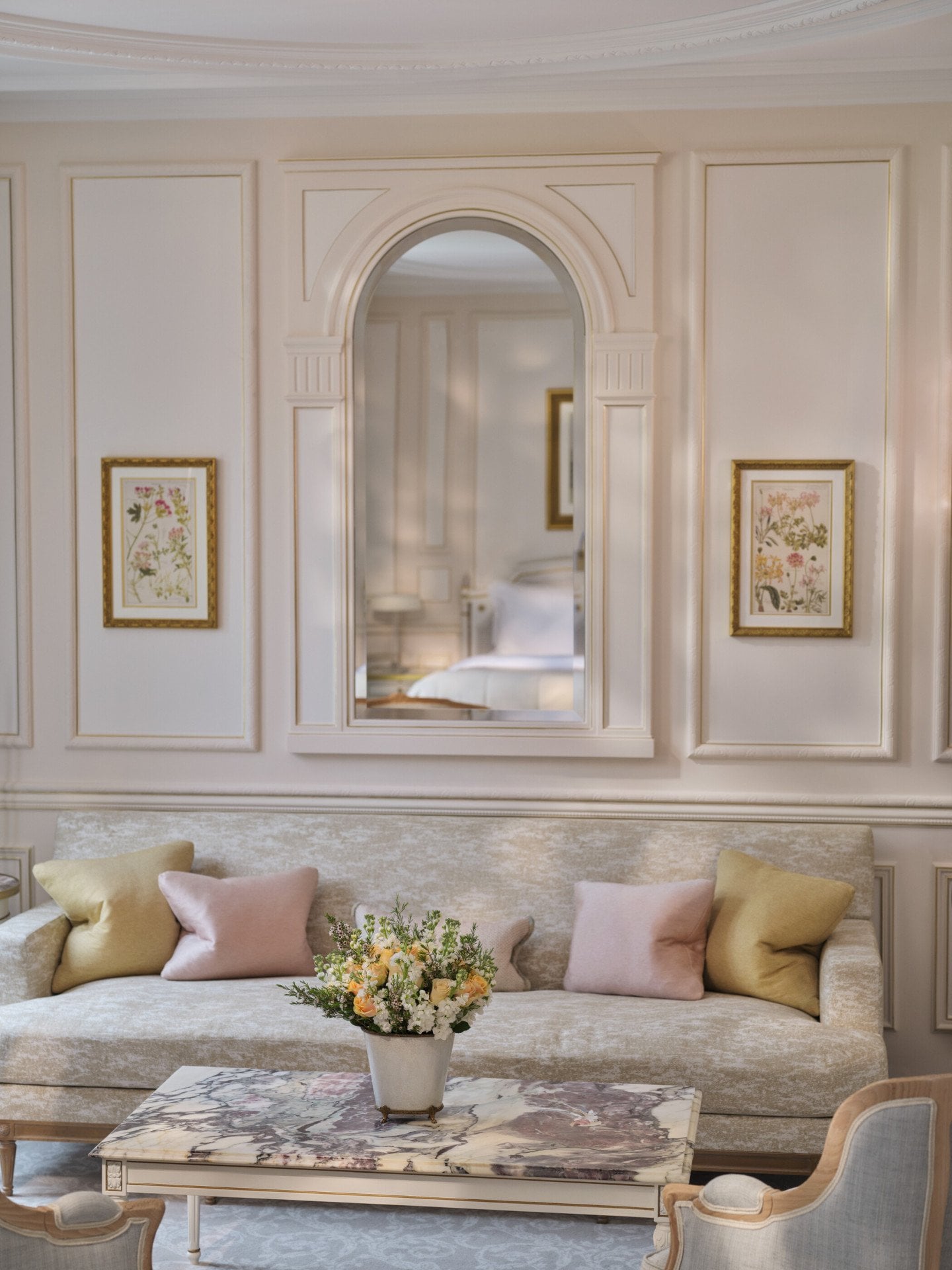 Livingroom area of a Deluxe Junior Suite with the table made with stone marquetry, the pillows on the couch and the mirror which reflect the bed, at Le Meurice, Paris