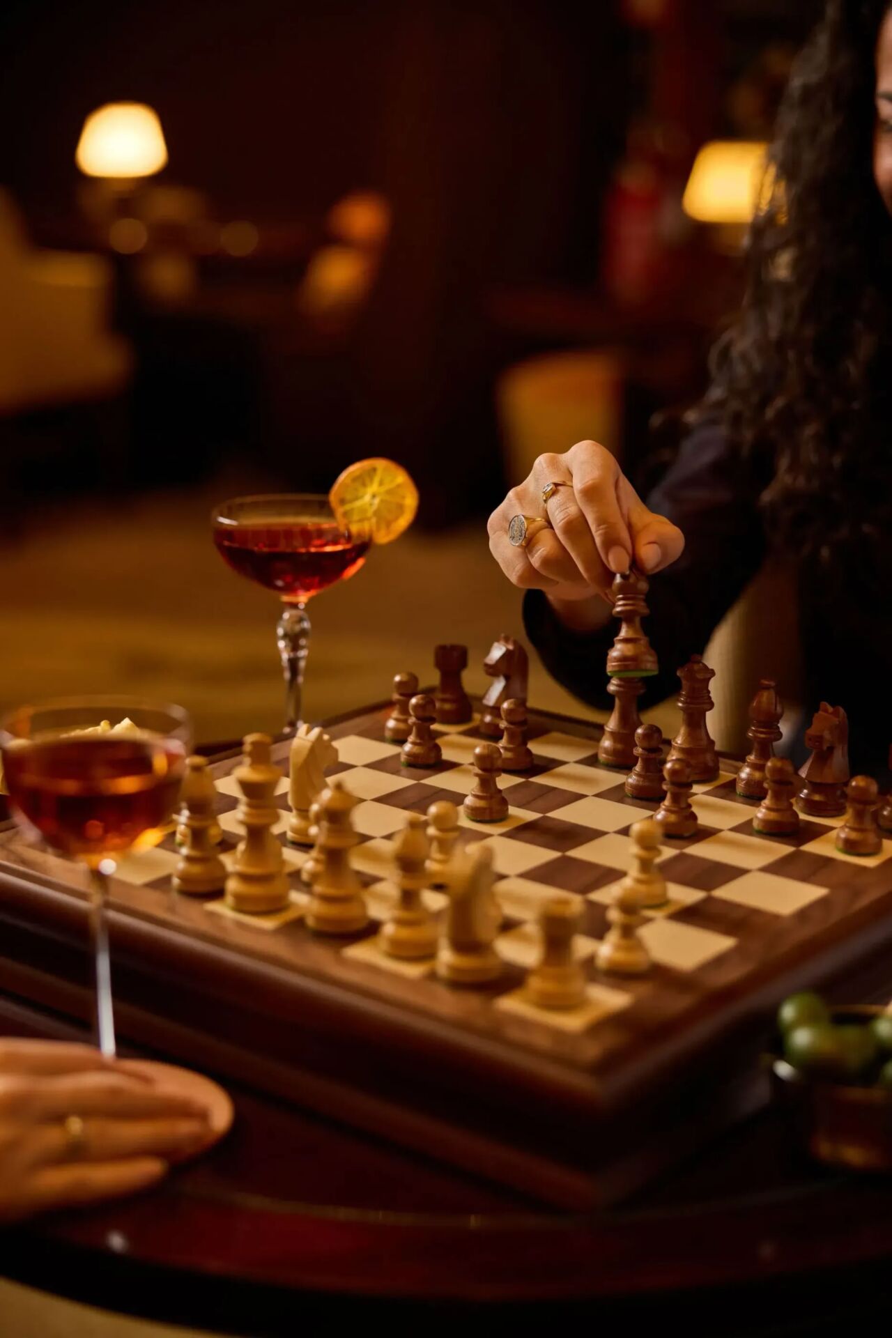 people playing Chess at Principe Bar with cocktails and olives on the table