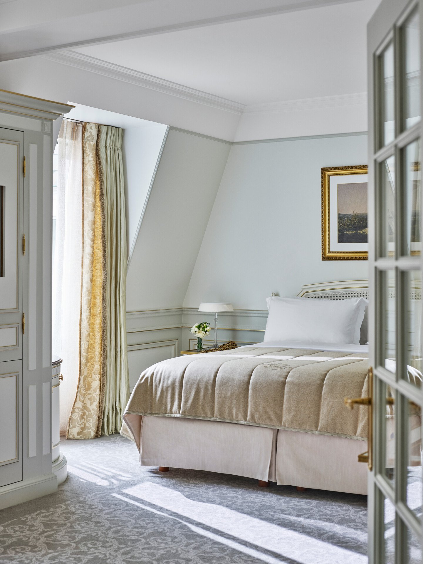Bedroom of a junior suite with light green and beige tones at Le Meurice, Paris.